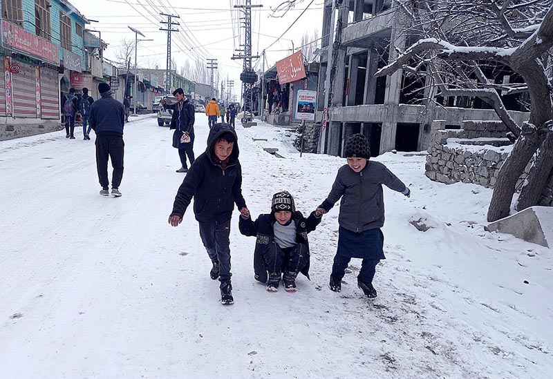 Children enjoying traditional skating on a snowy carpeted road during snow fall in Northern area of Pakistan