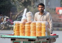 A vendor pushing handcart loaded with traditional sweet item (gachak) to attract the customers at Clock Tower Chowk