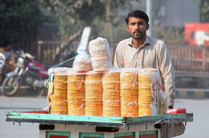 A vendor pushing handcart loaded with traditional sweet item (gachak) to attract the customers at Clock Tower Chowk