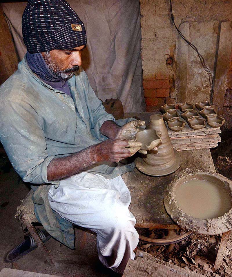 Senior artist making traditional clay pottery at his workplace.