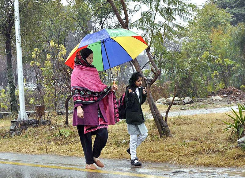 Ladies on the way walking on a roadside under the cover of an umbrella during rain in the Federal Capital