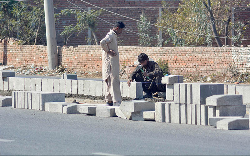 Construction daily wages workers fixing cement blocks on the center of he road for diversion of traffic near Sahu Chowk in the city