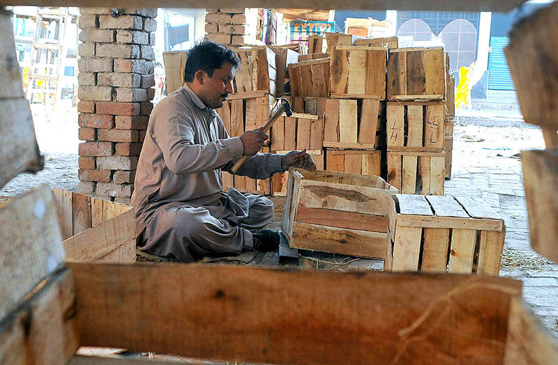 A man is making wooden boxes for trading of goods at his workplace