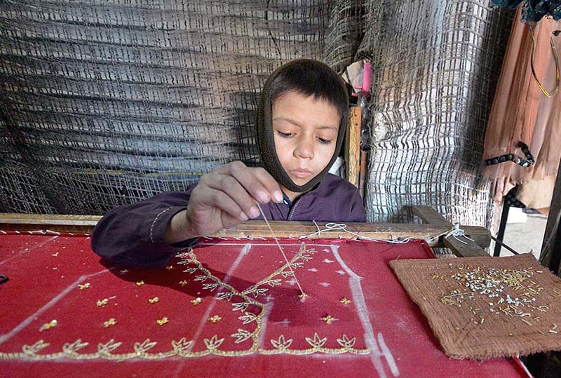 A child worker busy in zardozi traditional fancy embroidery for making bridal dress at his workplace near Meena Bazar