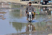 A motorcyclist passing through sewerage water accumulated on the road at site area