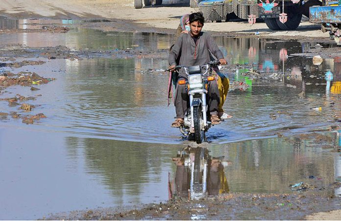 A motorcyclist passing through sewerage water accumulated on the road at site area