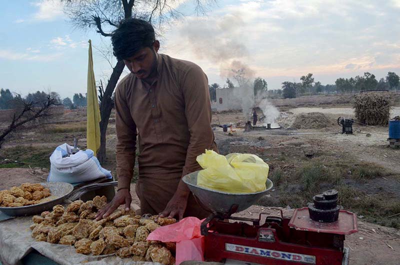 A vendor selling traditional sweet item gurr at Khushab road