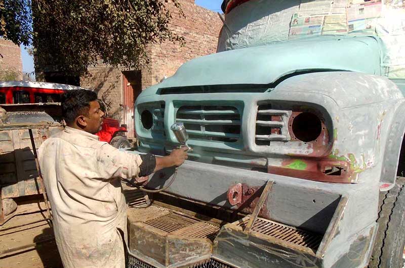 A painter busy in painting truck in his workshop at Sargodha road.
