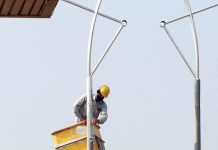 PHA worker is painting street light poles at Airport Road