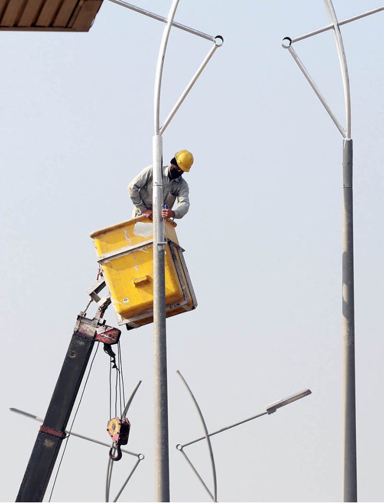 PHA worker is painting street light poles at Airport Road