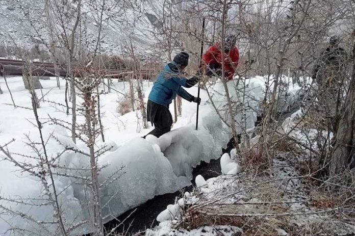 Workers busy in cutting Ice from the electricity canal for the proper water flow for electricity machine