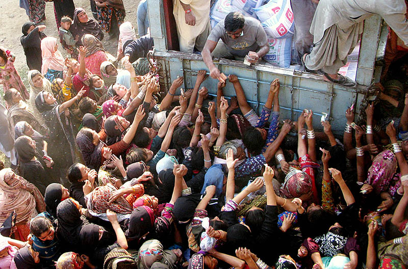 Many women purchasing flour bags on subsidized rates from a delivery truck at Latifabad.