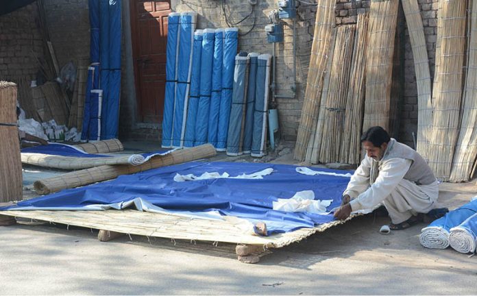 A worker is making traditional curtains (Chick) at his roadside setup