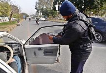 Capital police removing black sheet from a car window at Khayaban-e-Suhrawardy Road