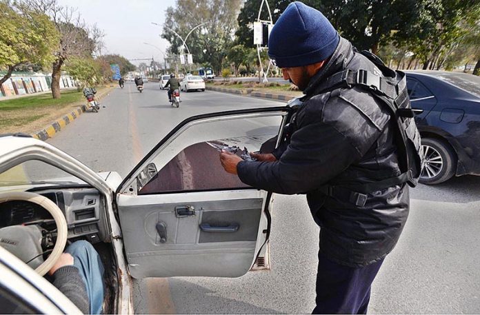 Capital police removing black sheet from a car window at Khayaban-e-Suhrawardy Road