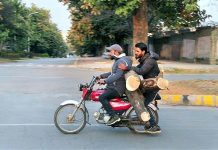 Motorcyclist on the way while carrying tree logs at Sitara Market