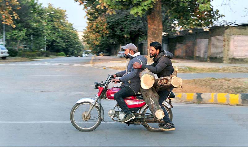 Motorcyclist on the way while carrying tree logs at Sitara Market