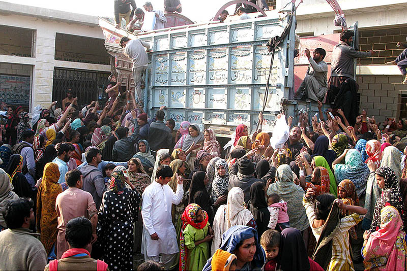 Many women purchasing flour bags on subsidized rates from a delivery truck at Latifabad.