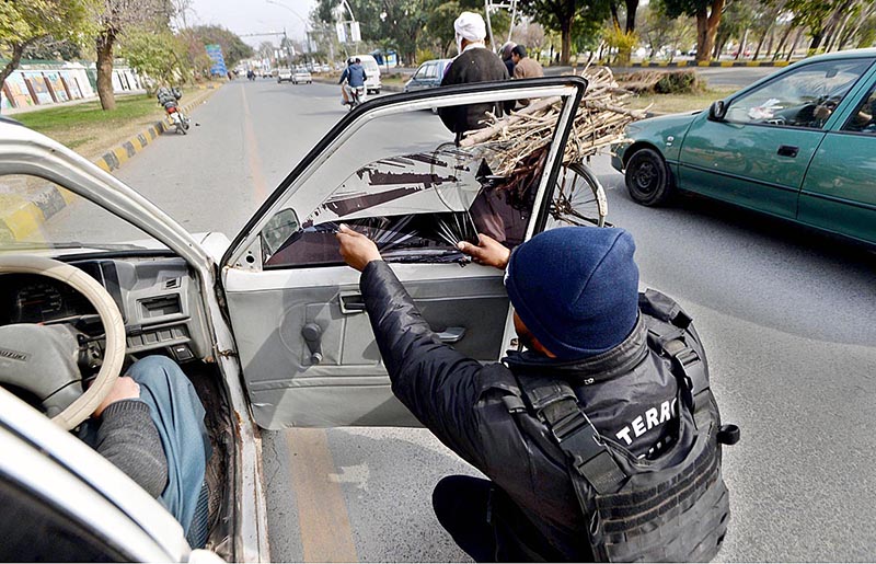Capital police removing black sheet from a car window at Khayaban-e-Suhrawardy Road