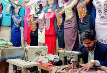 A worker busy in embroidery work on ladies wear at his workplace in Resham Gali