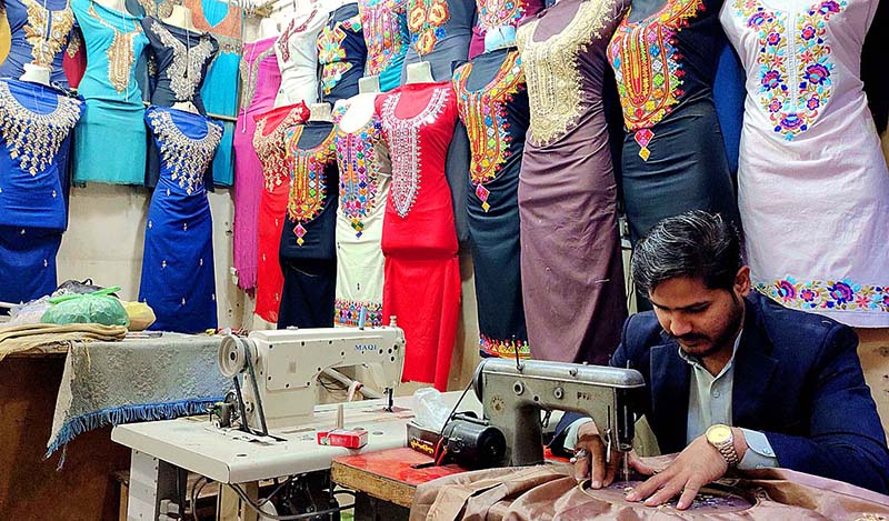 A worker busy in embroidery work on ladies wear at his workplace in Resham Gali