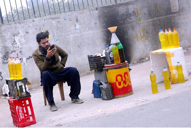 A vendor waiting for customers to sell petrol at his roadside setup