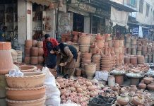 A man purchasing clay pots from a shopkeeper at Daulat Gate