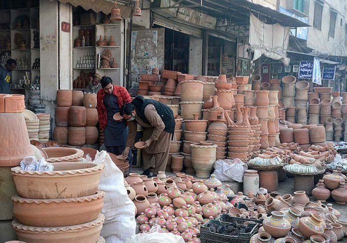 A man purchasing clay pots from a shopkeeper at Daulat Gate