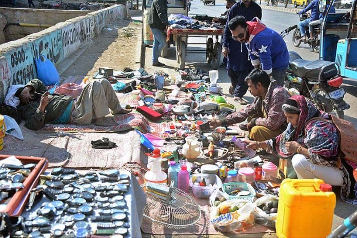 People selecting used household items at a roadside stall
