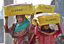 Women street vendors on the way while carrying blankets on their heads for selling at Gul Muhammad Khoso Village Road in the city