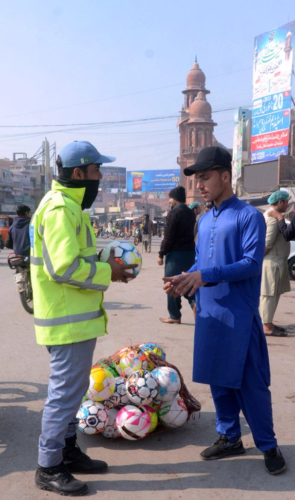A young vendor selling footballs to attract customers at Ghanta Ghar
