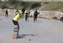 Youngsters playing cricket on the road.