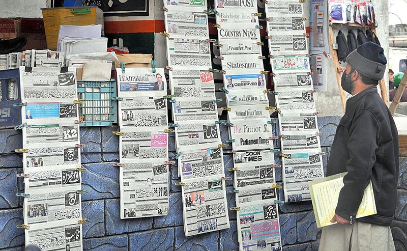 A citizen reads hanging newspapers outside a bookshop to gettingcurrent information at Aabpara market