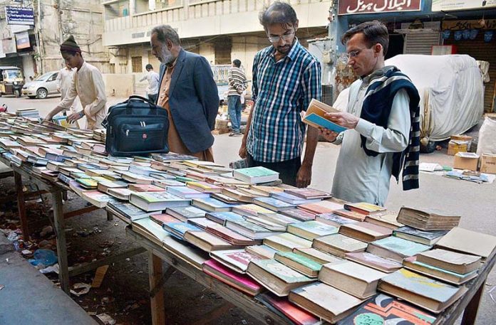 People purchasing old books at a roadside stall.