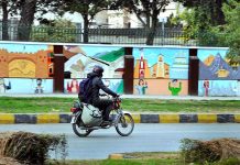 A motorcyclist passing near by a colorful painted wall near a local five star hotel
