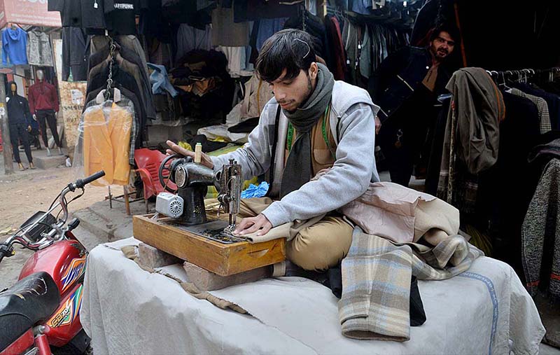 A tailor stitching and repairing used jackets for winter season in Anarkali in the provincial capital city.