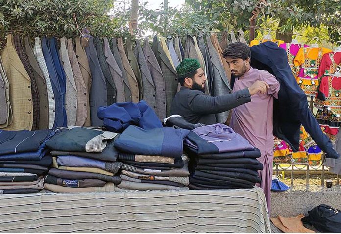 A vendor displaying and arranging coats to attract the customers at Press Club Road