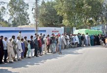 People standing in a queue to purchase subsidized wheat flour at a roadside stall in the metropolitan