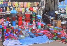 A vendor arranging and displaying plastic pots to attract customers at his roadside setup