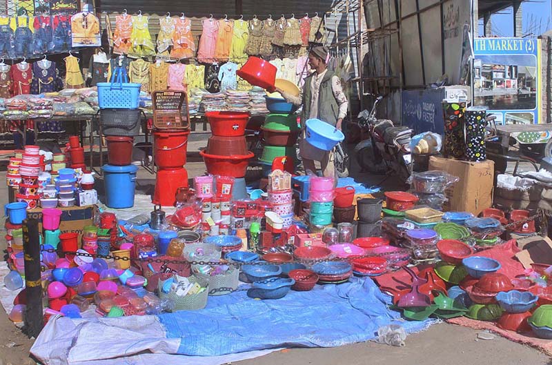 A vendor arranging and displaying plastic pots to attract customers at his roadside setup