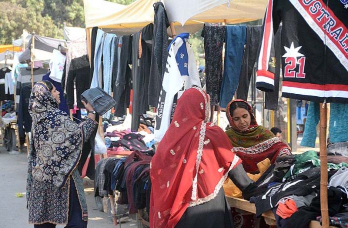 Women purchasing used clothes at a roadside stall