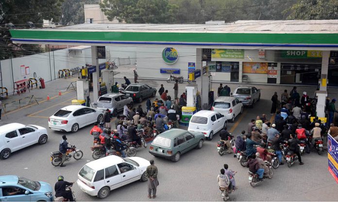 A large number of motorcyclists standing in a queue to get petrol during a shortage of petrol in the city