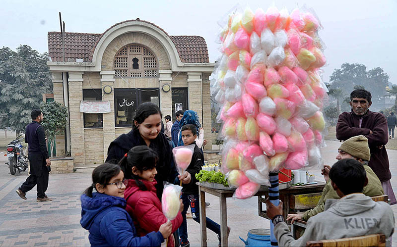 Children are buying cotton candy from a roadside vendor at Greater Iqbal Park