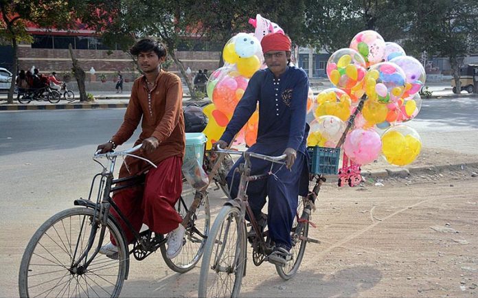 Young vendors selling balloons on their bicycles
