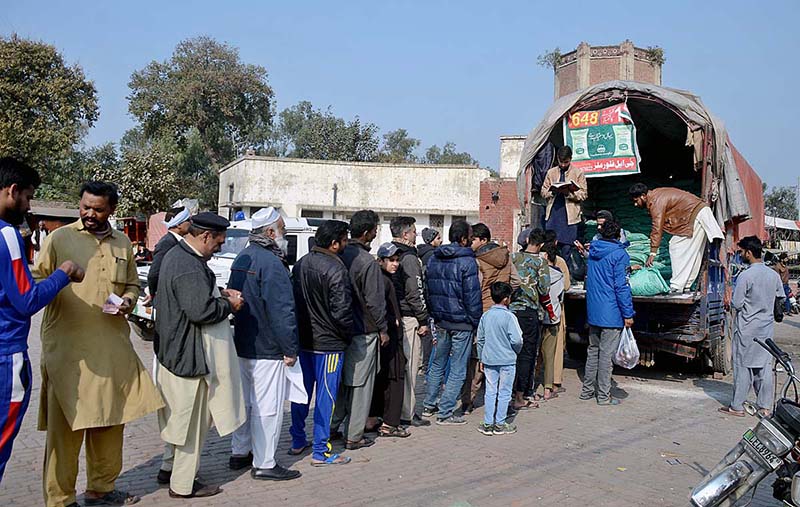 A large number of people standing in queue to get wheat flour bags at Wahdat road model bazaar.