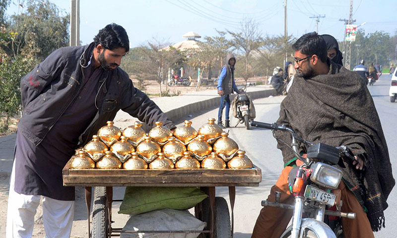 A street vendor is displaying and selling clay-made Golden color money banks to attract customers