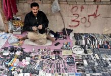 A technician repairing old remotes and wrist watches at his road side make shift setup in Provincial Capital city