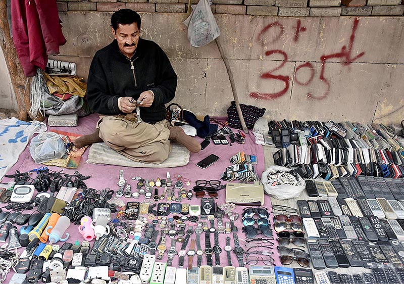 A technician repairing old remotes and wrist watches at his road side make shift setup in Provincial Capital city