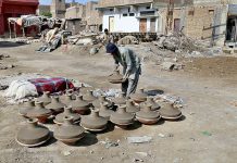 A potter placing clay pitchers in the sunlight for dry purpose at his work place Jamshro road