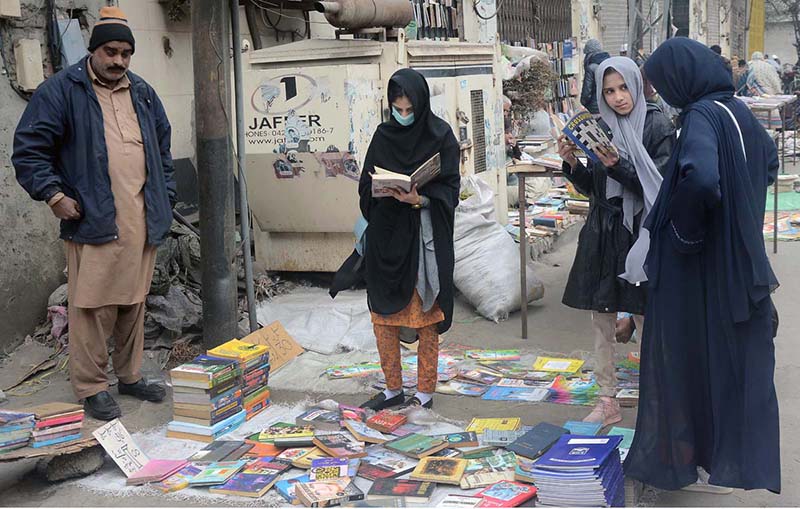 Women selecting old books on a roadside stall at Provincial Capital.